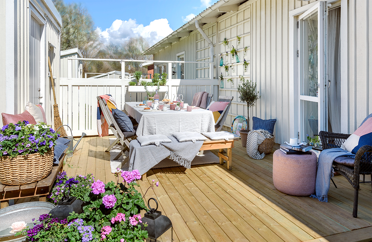 Ljus uteplats med träaltan fylld med växter och ett stort matbord