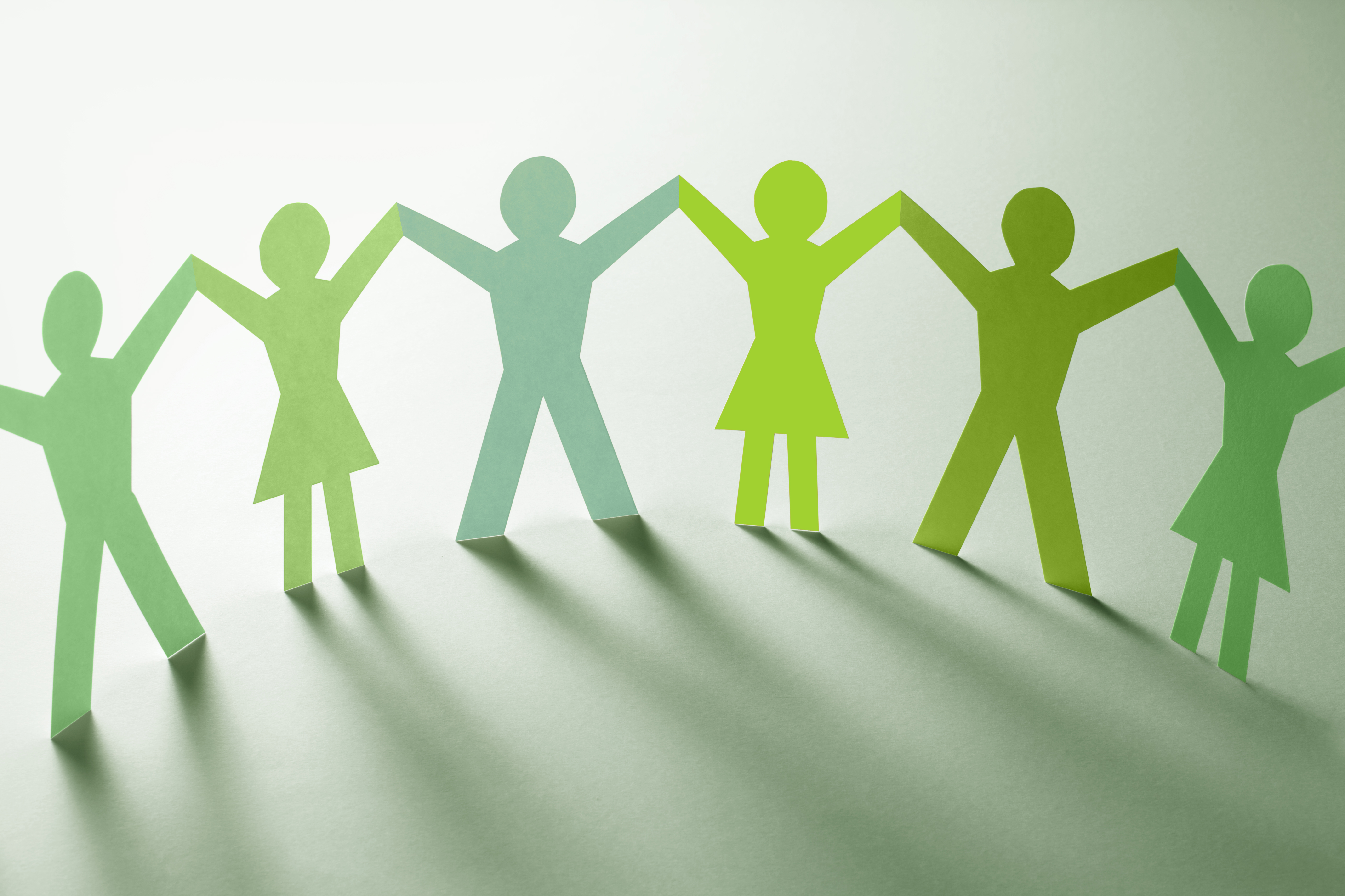 Gröna pappersfigurer som håller varandra i handen